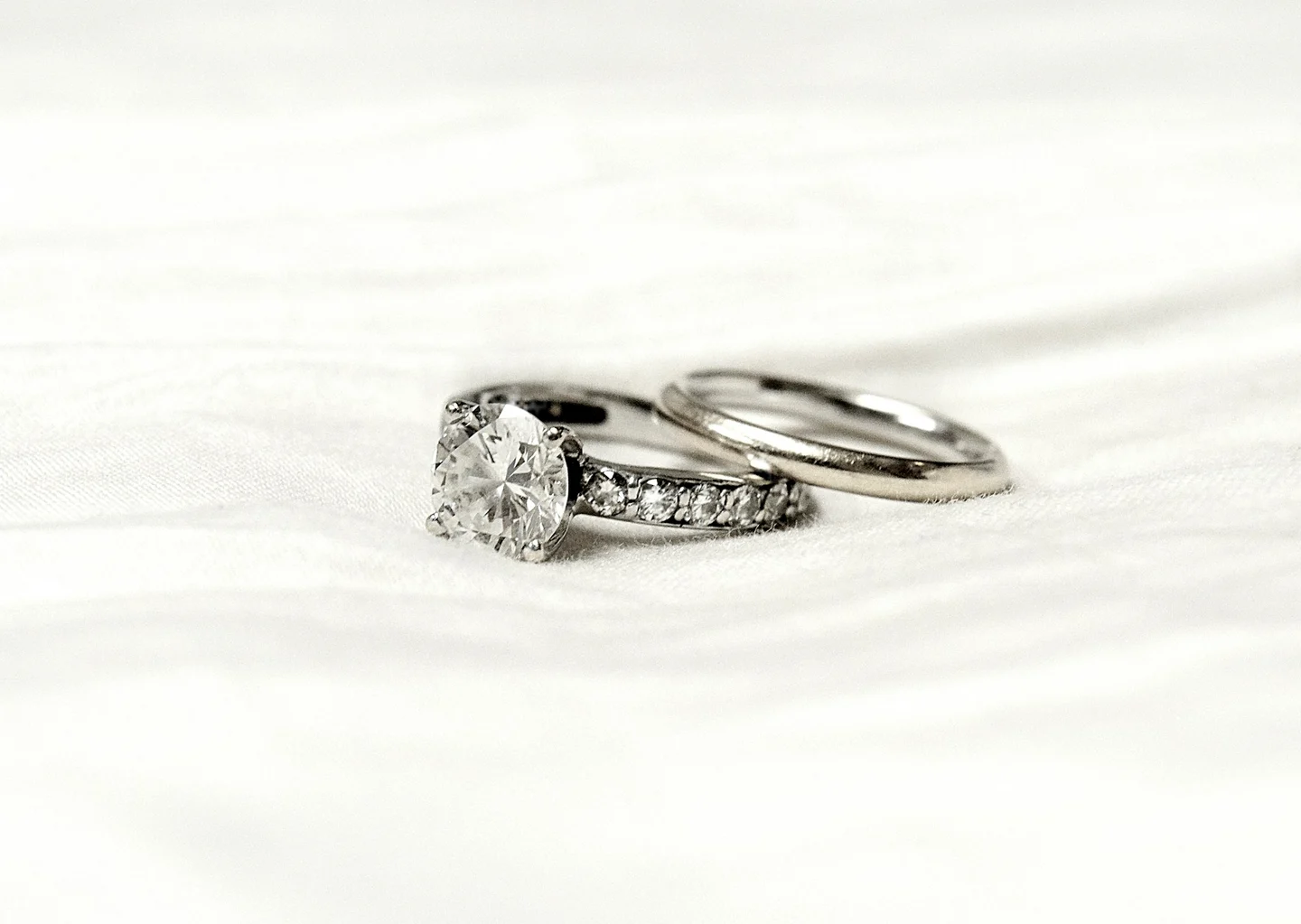 Diamond engagement ring and wedding band resting on white woven fabric
